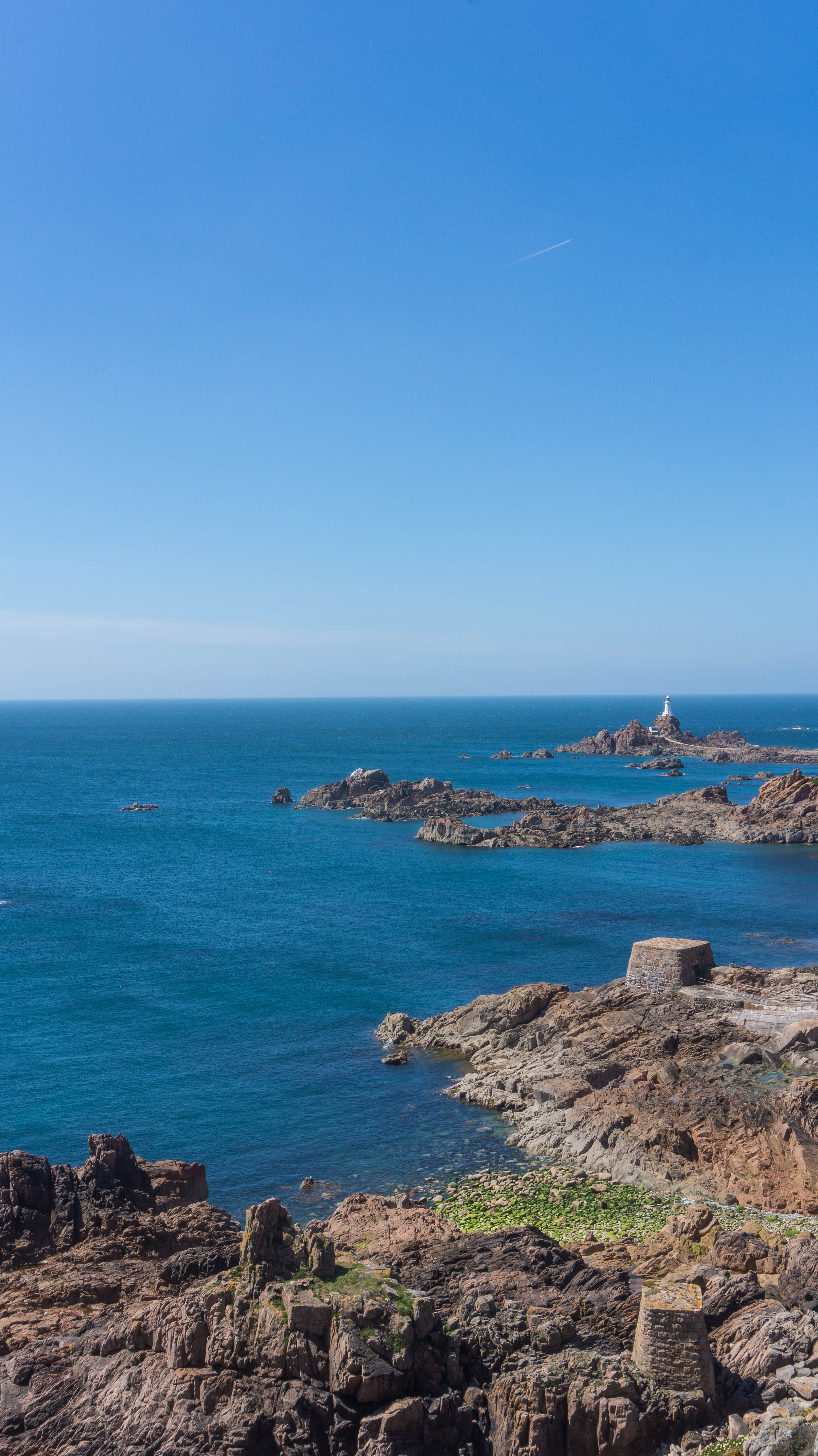 La Corbiere Lighthouse with derelict salt works buildings in foreground.