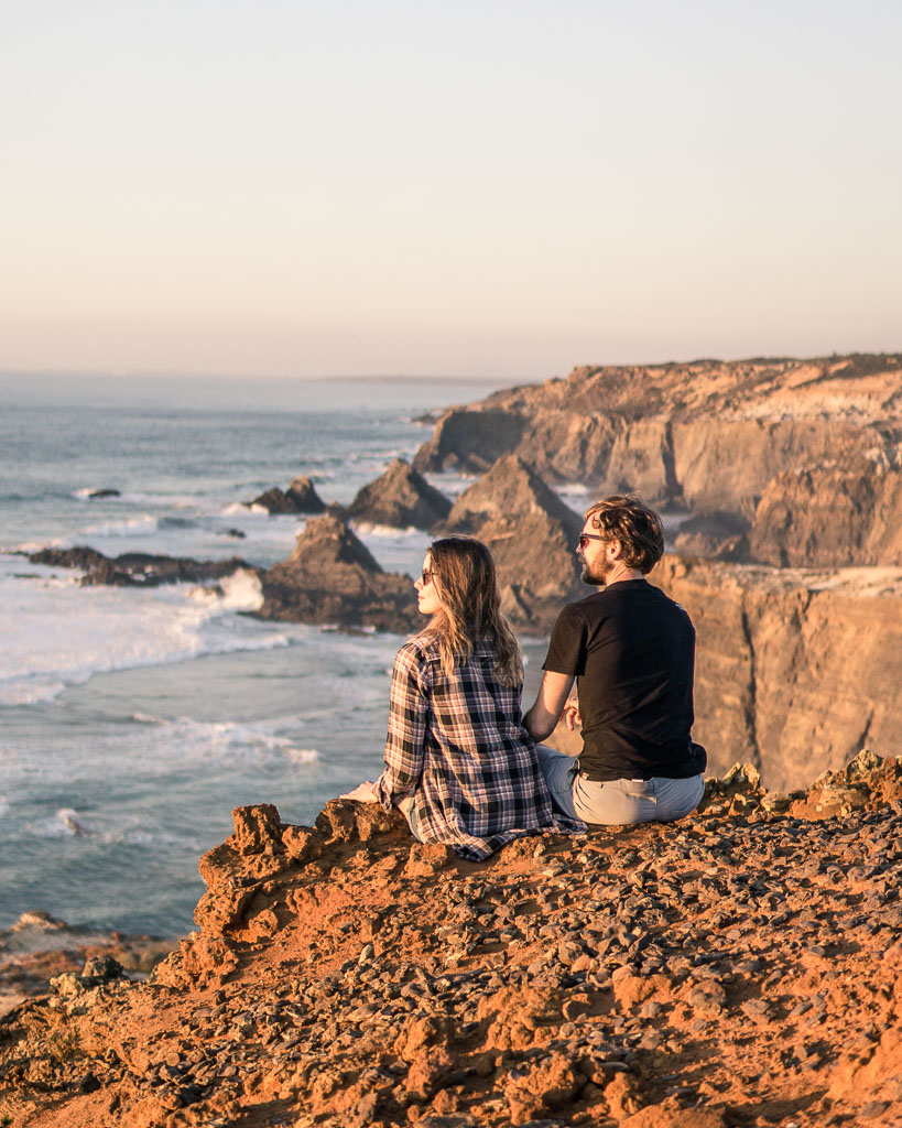 Luke & Nell watch the sunset on the red rock along the Portuguese coast