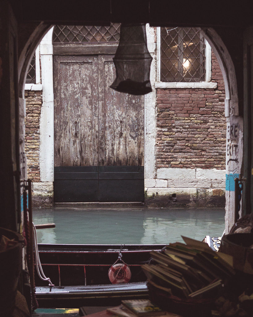 View from within famous Venice bookshop Libreria Acqua Alta out acros books and to the canal