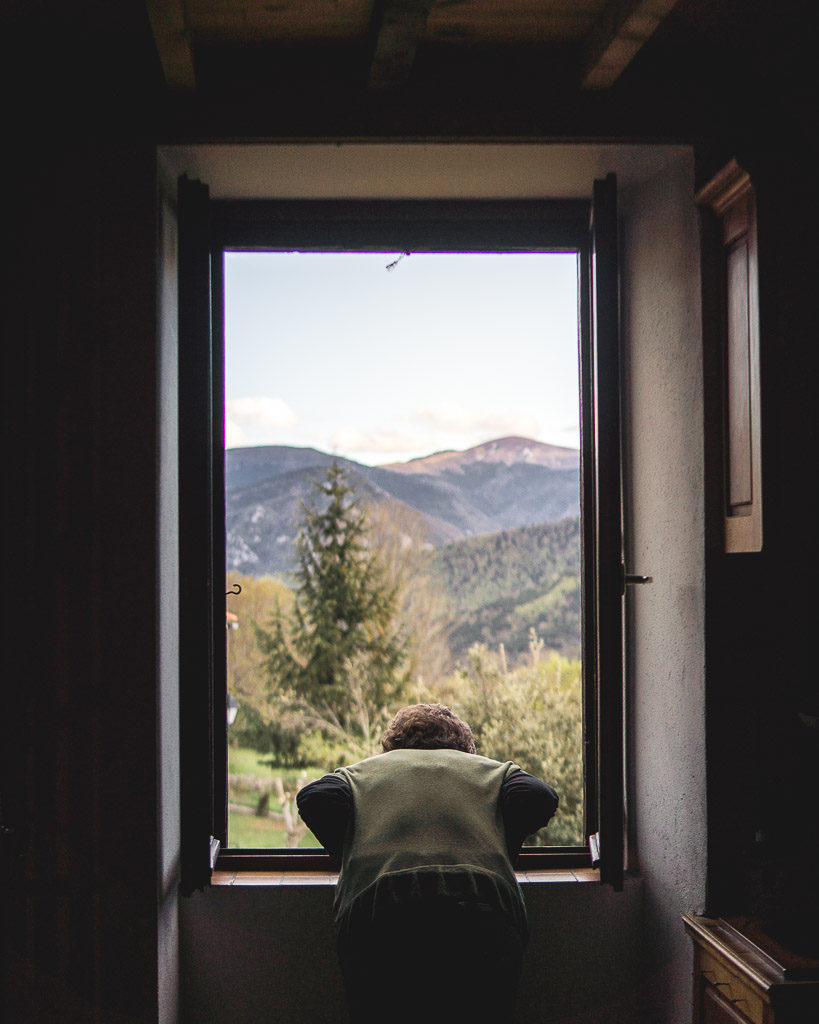 View of owner looking out of the window of the gîte with mountains in the distance.