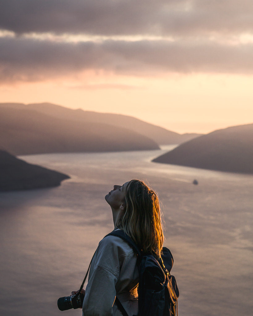 Portrait of Nell during the long golden hour of the Faroe Islands summer with an Atlantic channel in the background.