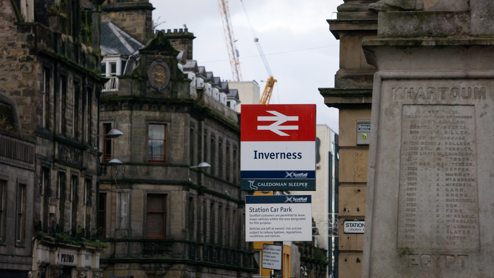 Inverness station sign with streets in background