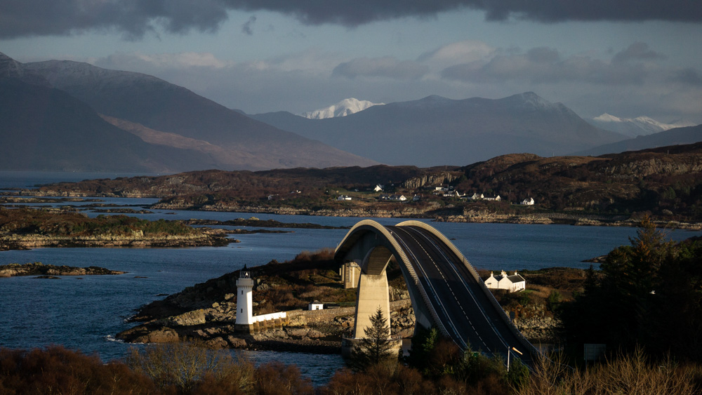 Skye Bridge with lighthouse and mountains in background