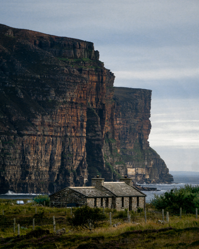 Rackwick cottage on the island of Hoy with towering sea cliffs in background